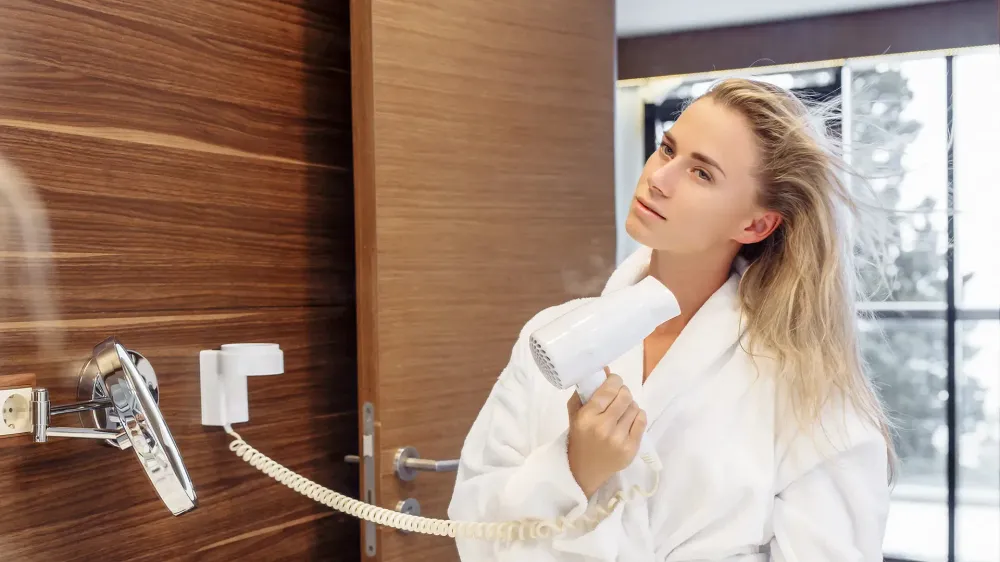 woman hotel room drying hair bathrobe bathroom